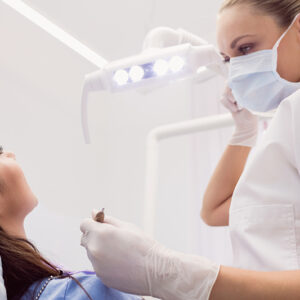 Dentist examining female patient in clinic